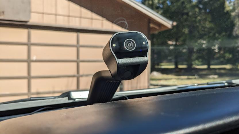 A Ring Car Cam installed on the dashboard of a car with a garage door in the background, seen from a drivers perspective.