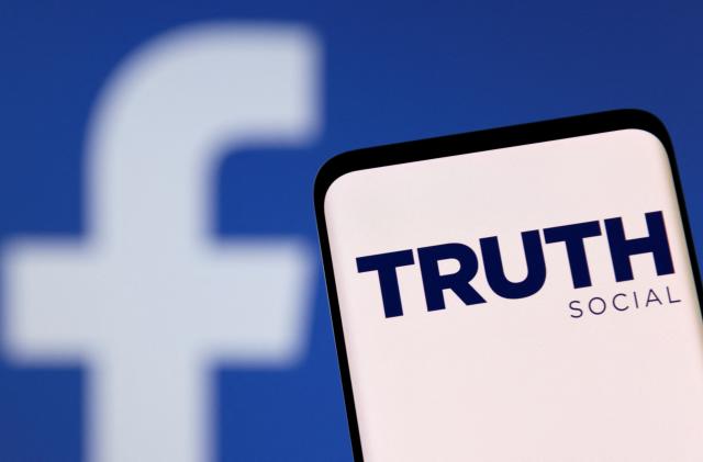 The Truth social network logo is seen on a smartphone in front of a display of the Facebook logo in this picture illustration taken February 21, 2022. REUTERS/Dado Ruvic/Illustration