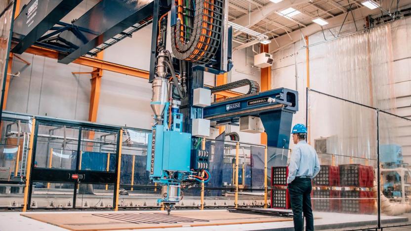 A man stands next to a giant 3D printer.