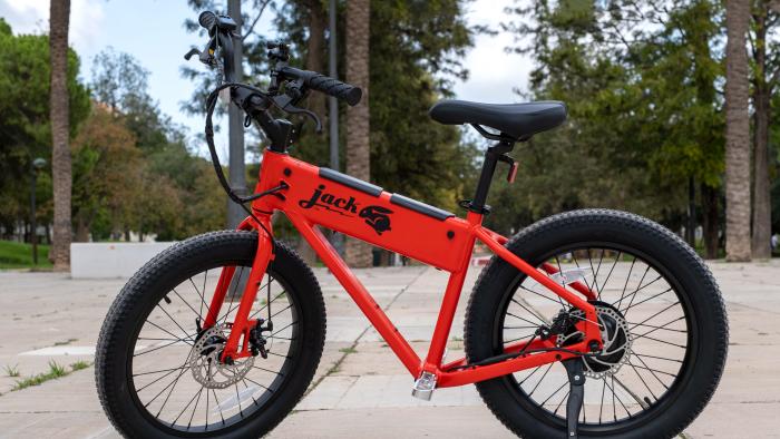 The red Jackrabbit mini e-bike is pictured riderless in a park.