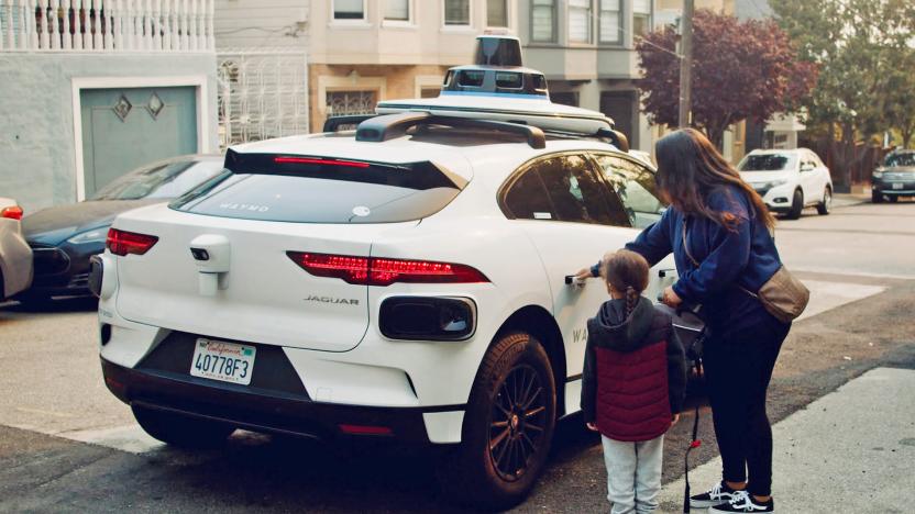 A Waymo Trusted Tester (woman and child) get in to a self-driving white jaguar SUV.