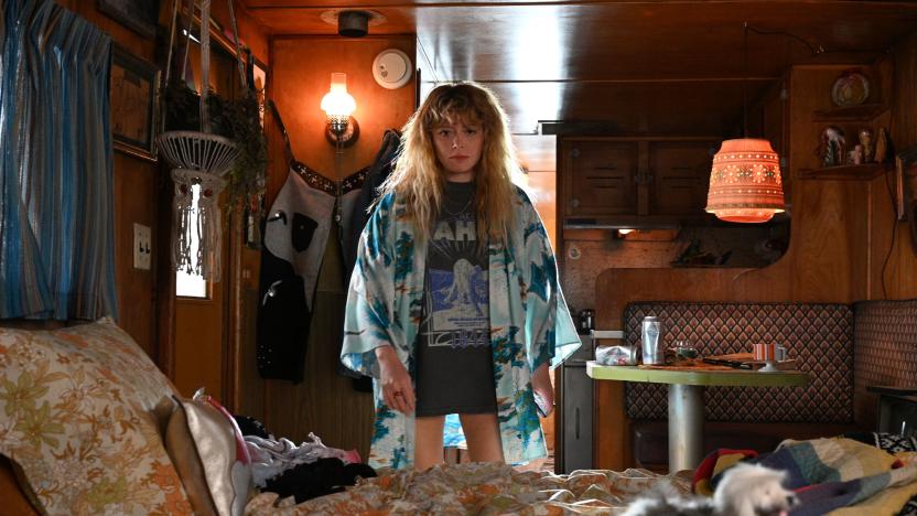 Image of actress Natasha Lyonne, star of the new series 'Poker Face', staring toward the camera and the middle distance. She is in a wood-pannelled room with distinctly retrograde styling, evoking memories of terrible holidays from the '70s. 