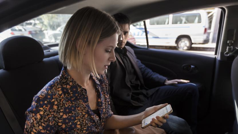 Beautiful young couple man and woman, businesswoman and businessman sitting together in the back of a car on a beautiful sunny day looking at phone, texting or emailing, Commuting to work, lunch date, meeting or going to the airport