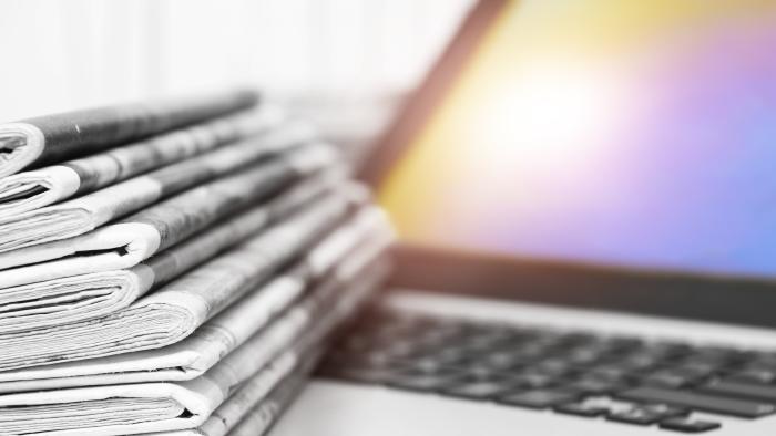 Newspapers and Open Laptop with Blue Screen. Lots of Business Journals and Computer. Magazines with News and Notebook Connected to Internet for Latest Data. Concept for Information and Communication