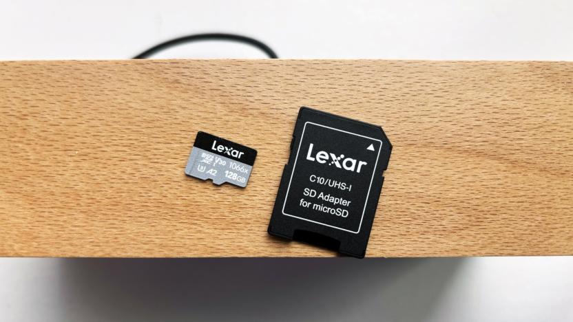 A silver and black Lexar Professional 1066x microSD card and its black SD card adapter rest on top of a brown wooden shelf above a white window sill.