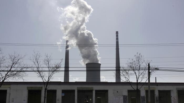 A man selling brooms rides his bicycle past abandoned buildings in front of a chimney billowing smoke from a nearby coal-burning power station in Beijing March 10, 2010. China signed up, along with India, to the Copenhagen Accord for fighting climate change on Tuesday, joining almost all other major greenhouse gas emitters in endorsing the non-binding pact. REUTERS/David Gray (CHINA - Tags: POLITICS ENVIRONMENT BUSINESS)