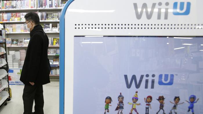 A shopper is seen behind a advertisement board of Nintendo Co Ltd's Wii U game console at an electronics retail store in Tokyo January 29, 2014. Nintendo Co Ltd, facing a third year of losses, is getting lots of unsolicited advice on how to squeeze more out of its Mario franchise and revive its fortunes after admitting that its Wii U game console has been a flop. REUTERS/Yuya Shino (JAPAN - Tags: BUSINESS SCIENCE TECHNOLOGY)
