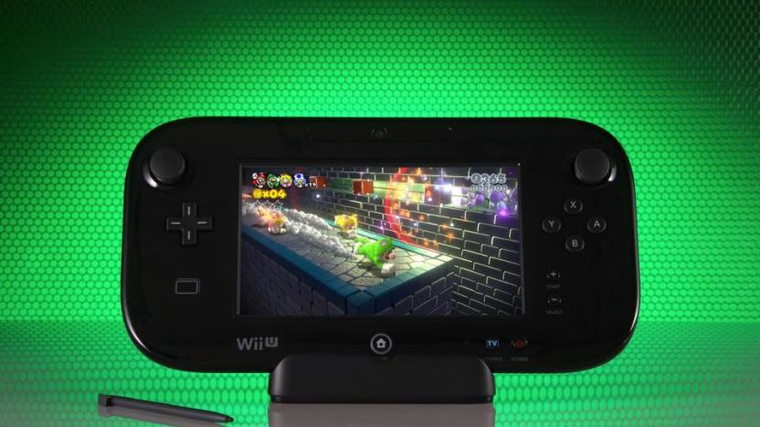 The Wii U gamepad propped up in front of a green honeycomb-style background. Its stylus sits next to it, and it has a prominent reflection below.