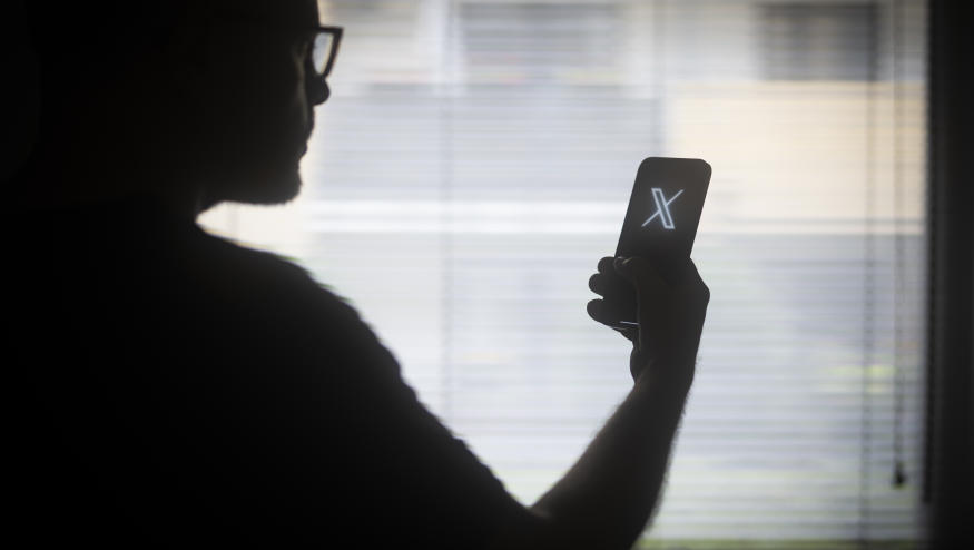 The X logo is seen on a mobile device held in the hand of a man with glasses in this illustration photo in Warsaw, Poland on 29 August, 2023. (Photo by Jaap Arriens/NurPhoto via Getty Images)