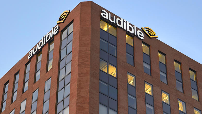 View from below of the top corner of Audible’s headquarters. The brown-red brick building has Audible logo signs on either side of the corner.