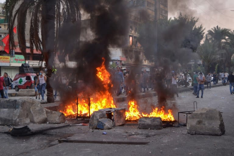 Lebanese anti-government protesters stand behind a barricade during a demonstration in Beddawi town on the outskirts of the port city of Tripoli on Saturday (AFP Photo/Fathi AL-MASSRI)