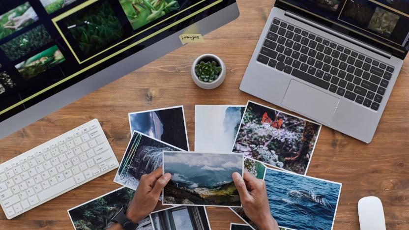 Minimal background composition of male hands holding printed photographs over textured wooden desk, photographers office concept, copy space