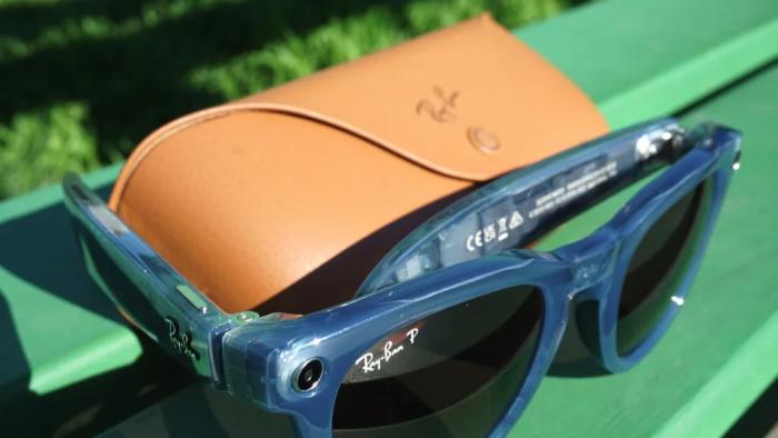 A paid of sunglasses propped against its case on a green bench.