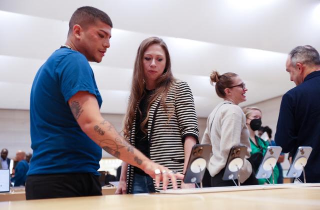 Chelsea Clinton is shown the Apple iPhone 14 range by a worker at the Apple Fifth Avenue store in Manhattan, New York City, U.S., September 16, 2022.  REUTERS/Andrew Kelly