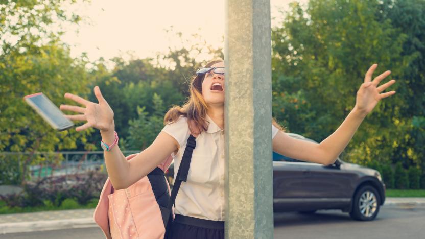 Portrait of young inattentive girl, distracted by mobile phone. Girl crashed into street post, dropped phone.