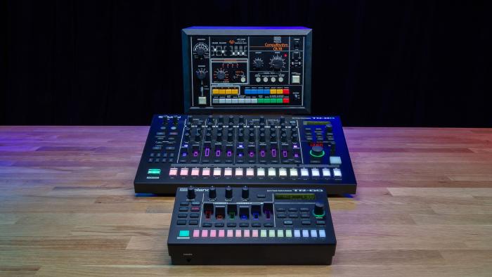 The Roland TR-8S, TR-6S and CR-78 are lined up front-to-back on a wooden table with a black background.