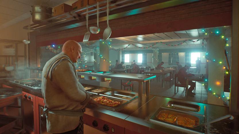 A cook works behind the counter of a cafeteria with hotplates of food ready to serve.