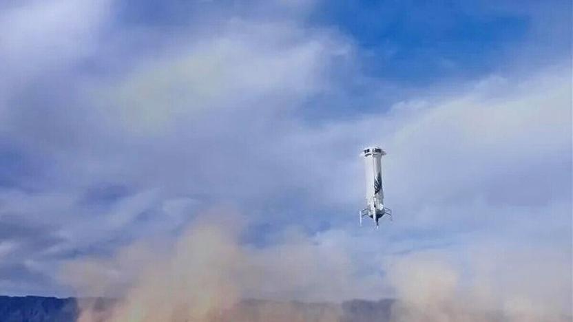 An image of a the Blue Origin New Shepard booster rocket lowering to Earth.  