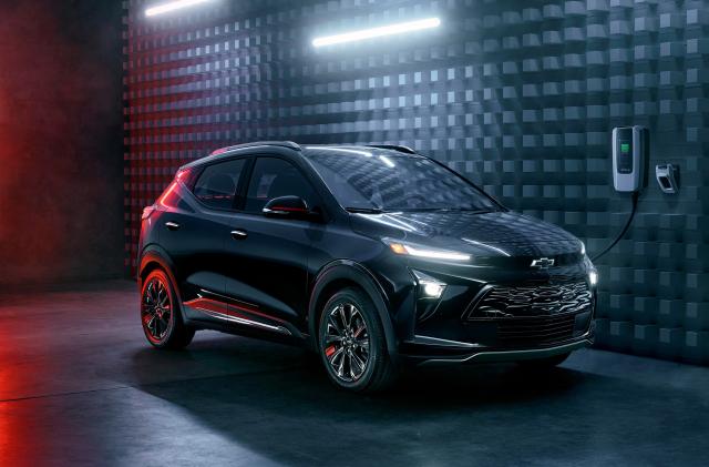 The 2023 Chevy Bolt charging in a modern black space with white and red neon highlights.