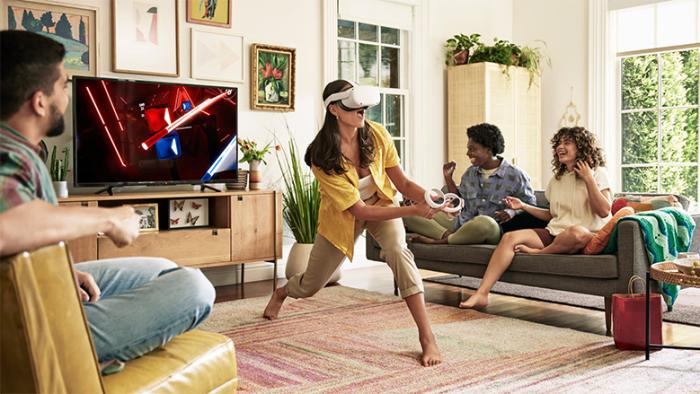 A person uses a Meta Quest 2 headset in a living room as others look on from couches.