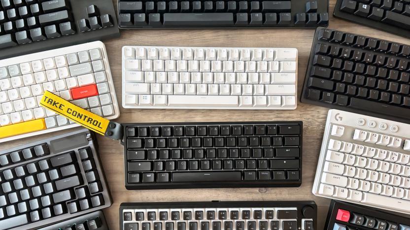 A variety of gaming keyboards rest in close proximity on a light brown wooden table, including the Wooting 60HE, Razer Huntsman Mini, G.Skill KM250 RGB, Logitech G PRO TKL, ASUS ROG Azoth, ASUS ROG Strix Scope II 96 Wireless, Razer Huntsman V2 TKL, Keychron V3 and Corsair K70 RGB TKL.