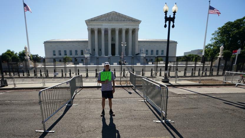 A man casts an early morning shadow while holding a sign saying "Keep Roe" as he protests in front of the U.S. Supreme Court after the court recently overturned the landmark Roe v Wade abortion decision with their ruling in the Dobbs v. Jackson Women's Health case, in Washington, U.S., June 28, 2022. REUTERS/Kevin Lamarque