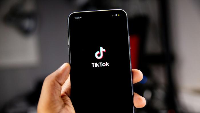 A hand holding a phone with TikTok on it.