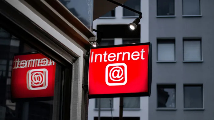 A red sign hanging outside a building. It reads "Internet" and includes an "at" symbol.
