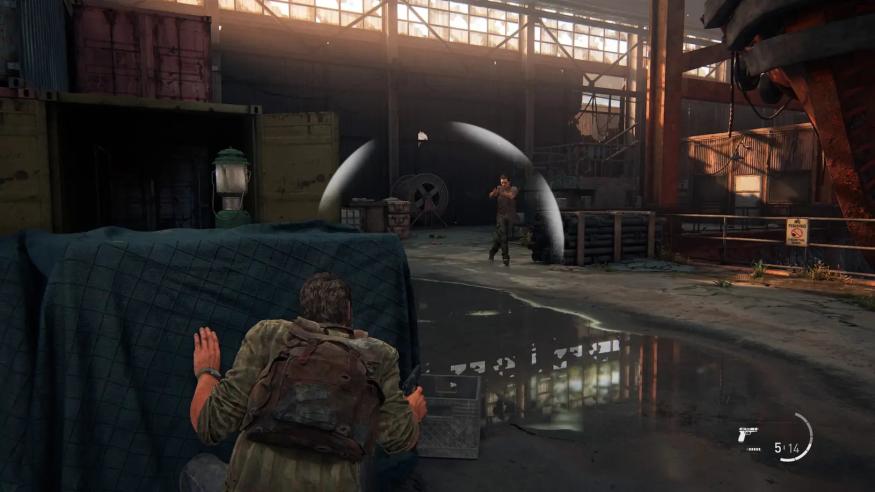 A screenshot of The Last of Us Part I, showing Joel taking cover as an enemy walks close by. An onscreen indicator shows the direction of noise created by enemies.