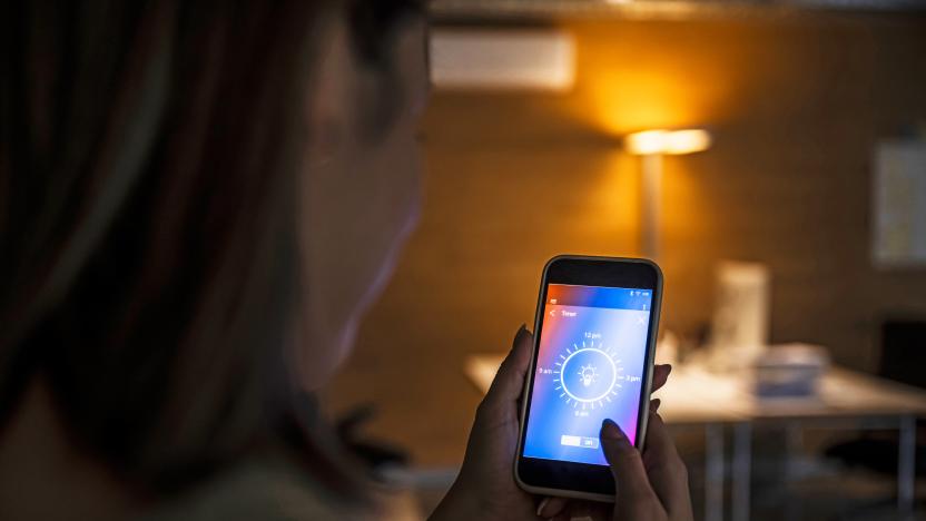 Woman using smart phone with light bulb icon screen at home.    