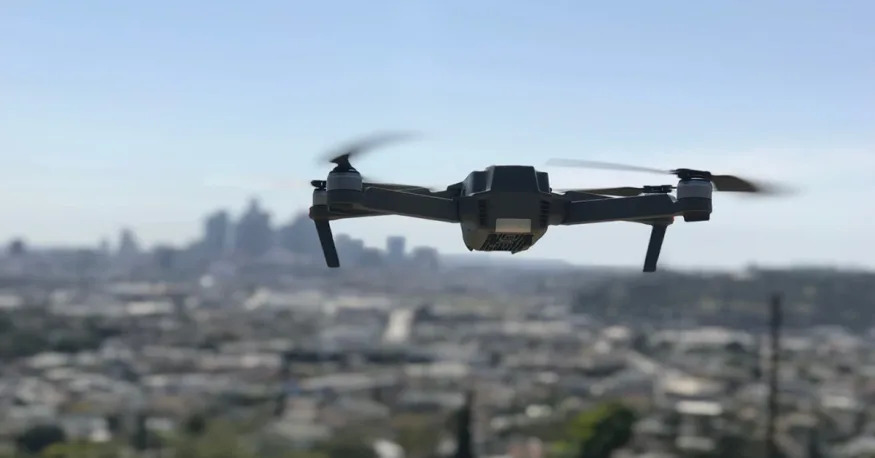 The Alpha Z PRO hovers in the air with a city skyline in the background.