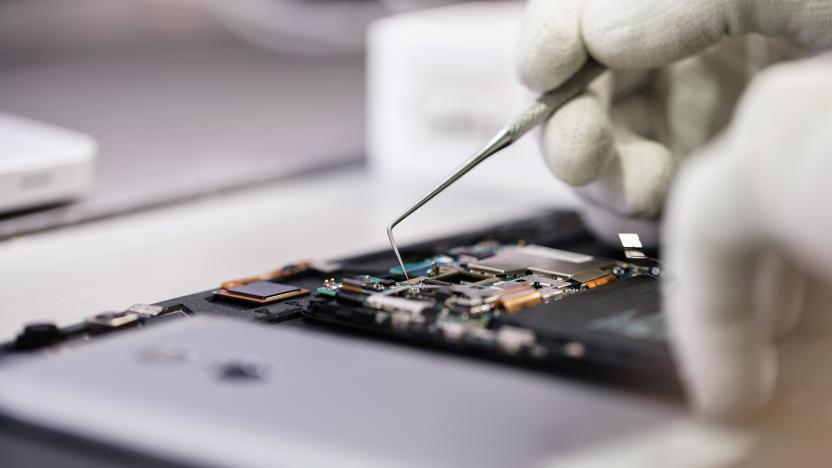 Work with a microscope. Microelectronics device. Close-up hands of a service worker repairing modern smartphone.