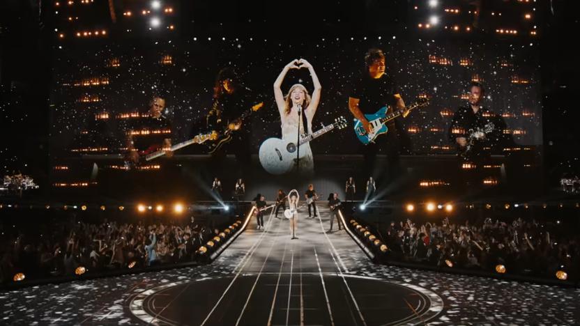 Image from Taylor Swift’s Eras Tour video. The singer and backup band stand on stage surrounded by thousands of cheering fans.