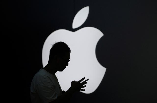 A man check his phone near an Apple logo outside its store in Shanghai, China September 13, 2023. REUTERS/Aly Song