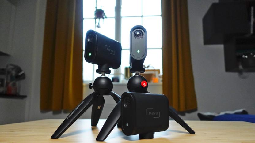 The Logitech Mevo Start live-streaming setup photographed on a small wooden countertop in someones apartment, with a window and curtains in the background.