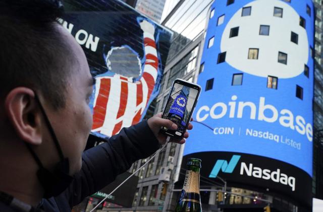 FILE - Coinbase employee Daniel Huynh holds a celebratory bottle of champagne as he photographs outside the Nasdaq MarketSite, in New York's Times Square, April 14, 2021. Coinbase rose, Friday, June 23, 2023, after winning a Supreme Court case. The crypto trading platform wanted to keep a dispute with a customer in arbitration, a process that many companies prefer over lawsuits in courts. (AP Photo/Richard Drew, File)