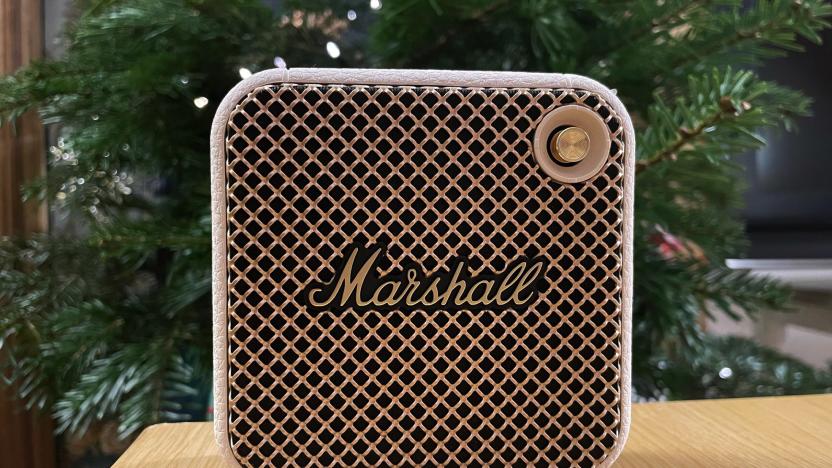 A white Marshall Willen Bluetooth speaker sits on a table with a holiday tree in the background.