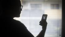 The X logo is seen on a mobile device held in the hand of a man with glasses in this illustration photo in Warsaw, Poland on 29 August, 2023. (Photo by Jaap Arriens/NurPhoto via Getty Images)