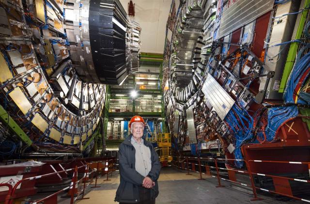 Peter Higgs standing in front of the Large Hadron collider.