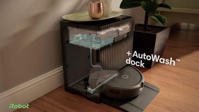 Roomba in a large docking station. Overlaid text: "+ Autowash dock."