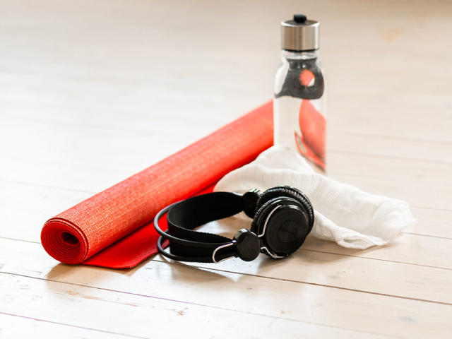 A red yoga mat on white hardwood floor in a domestic living room at home. Ready to be used in some home exercises.