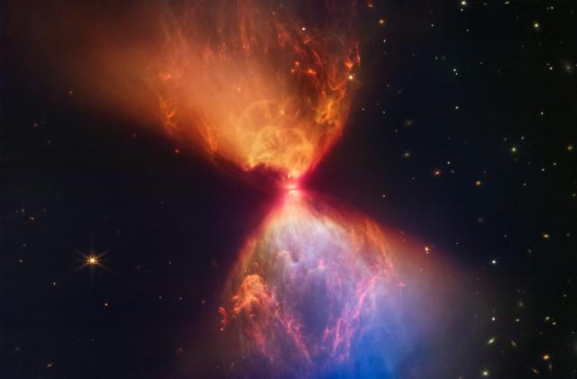 The protostar L1527, shown in this image from the NASA/ESA/CSA James Webb Space Telescope, is embedded within a cloud of material that is feeding its growth. Material ejected from the star has cleared out cavities above and below it, whose boundaries glow orange and blue in this infrared view. The upper central region displays bubble-like shapes due to stellar âburps,â or sporadic ejections. Webb also detects filaments made of molecular hydrogen that has been shocked by past stellar ejections. Intriguingly, the edges of the cavities at upper left and lower right appear straight, while the boundaries at upper right and lower left are curved. The region at lower right appears blue, as thereâs less dust between it and Webb than the orange regions above it.