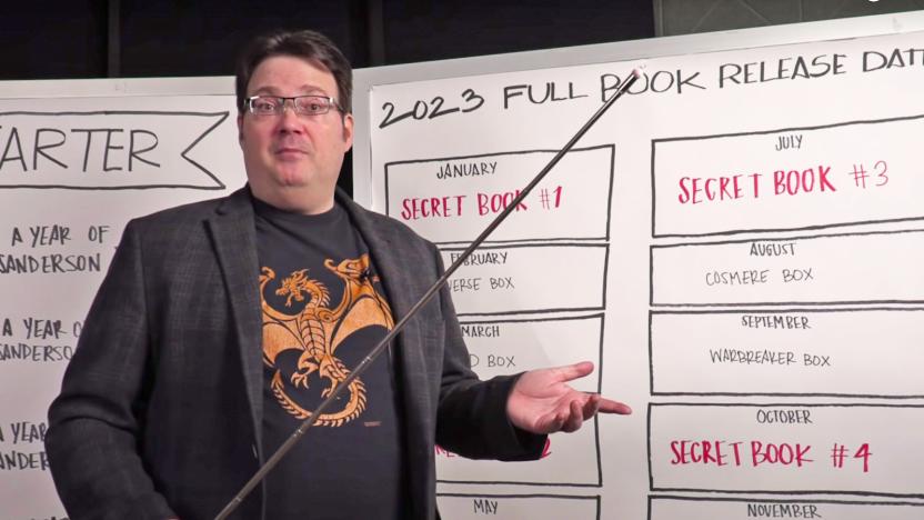 Sci-Fi author Brandon Sanderson stands in front of dry erase boards that show info about his planned new book.