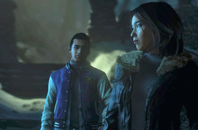 Two characters stand near each other, one a boy in a letterman's jacket looks at a woman standing in front of him and she's glancing to the side in this still from the video game Until Dawn. 