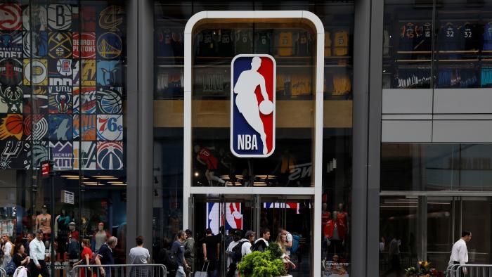 FILE PHOTO: The NBA logo is displayed as people pass by the NBA Store in New York City, U.S., October 7, 2019. REUTERS/Brendan McDermid/File Photo