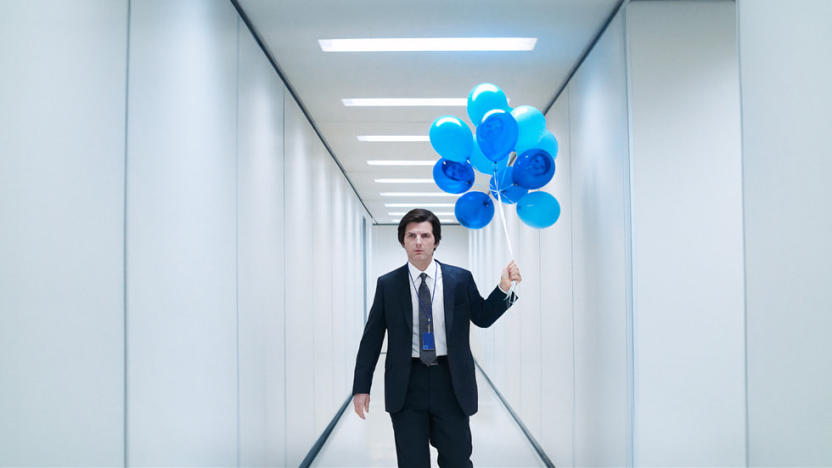 Adam Scott (wearing a suit) holds a bunch of blue blues in a white hallway in Severance.