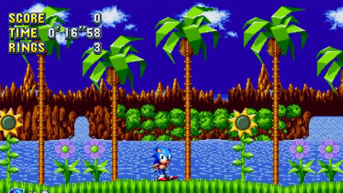 A screenshot of Sonic Mania Plus showing Sonic, an anthropomorphic blue hedgehog, against a background of computer-drawn beach and palm trees. 