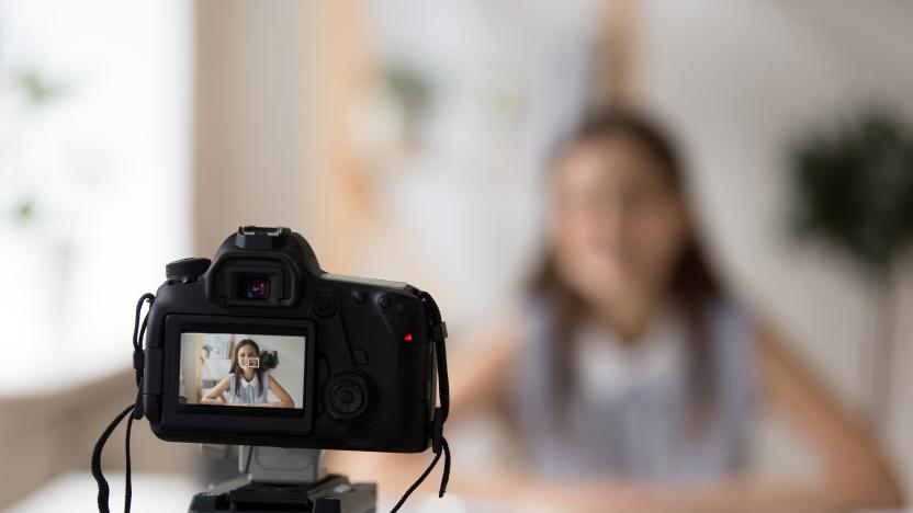 Professional camera shooting young smiling female tutor or coach making presentation or recording master class tutorial for channel, woman business vlogger filming video training for blog or website