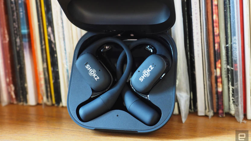 Close-up images of the Shokz OpenFit open-ear buds in grey with the charging case.
