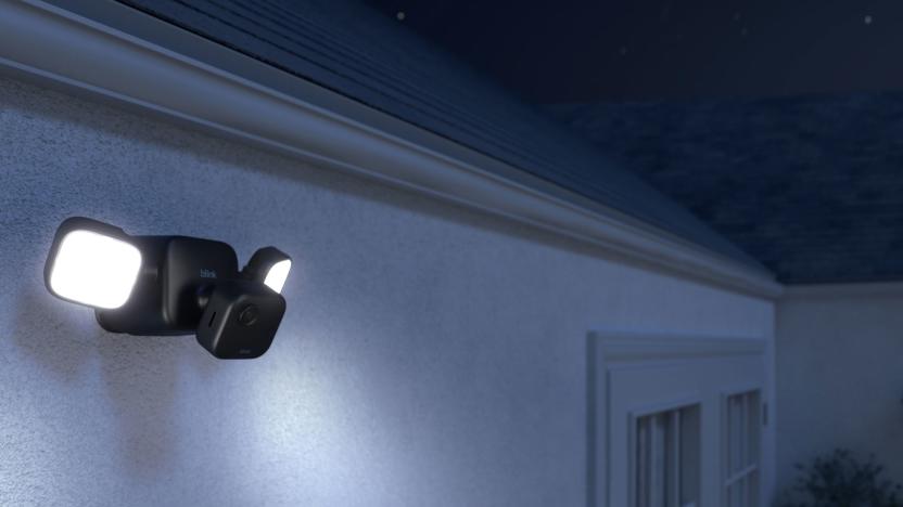 Image of the Blink Outdoor 4 with its external floodlight mount, sold separately, projecting light into the darkness. 